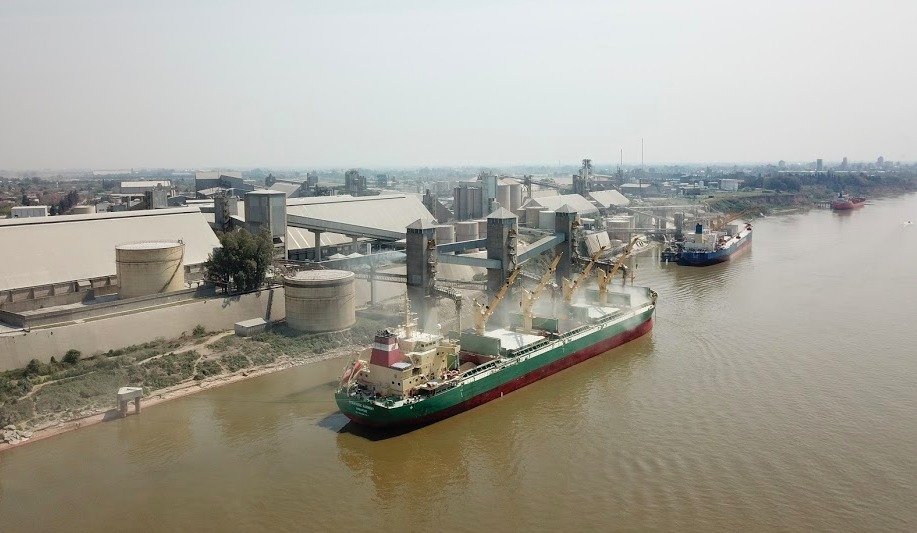 Vista aérea de un buque cargando cereal en una terminal sobre el río
